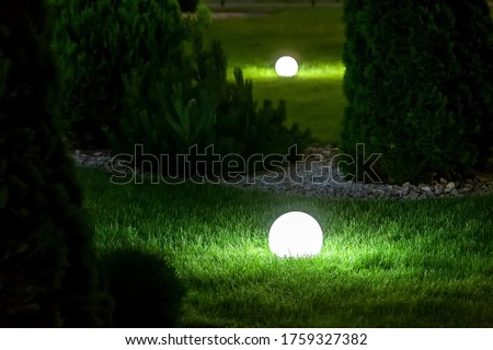 illumination backyard light garden with electric ground lantern with sphere diffuser lamp in the green grass lawn in outdoor park with landscaping, dark patio illuminate night scene nobody. Royalty-Free Stock Photo #1759327382