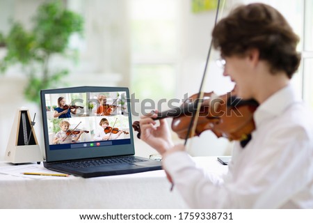 Violin lesson online. Teacher and child play violin via computer. Remote learning from home. Arts for kid. Kids with musical instrument. Video chat conference. Online music tuition. Homeschooling. Royalty-Free Stock Photo #1759338731