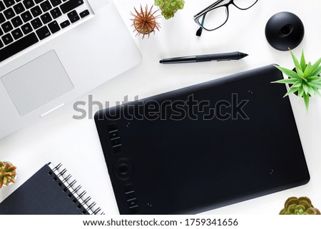 White office desk with graphic tablet and laptop. Office supplies. View from above.