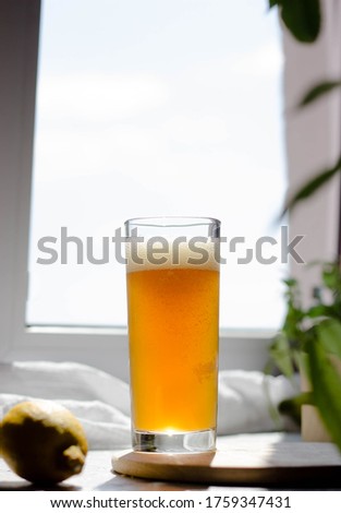 A yellow foaming drink is poured into a glass from a dark bottle. The brew in the glass