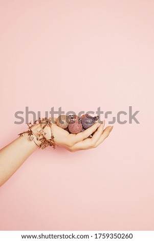 Christmas concept. Female hand holding Xmas balls decoration on pink background