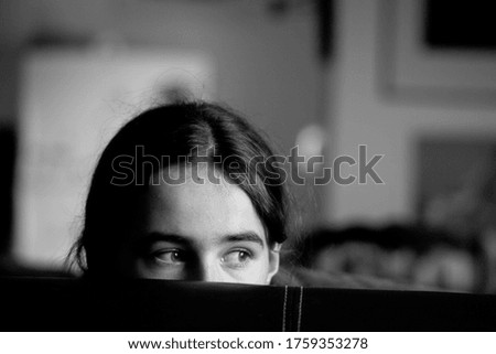Peering young girl black and white indoors