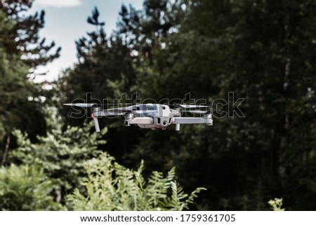 Drone hovering in the air with trees in the background. Outdoor photo