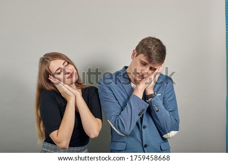 Sleeping with head laid on clasped hands as sweet dreams, eyes closed, close-up, gesturing asleep sign, resting. Young attractive couple boyfriend girlfriend two people, dressed black t-shirt