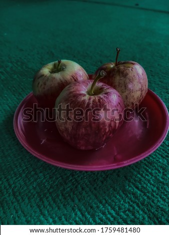 Picture of 3 apples on a red plate