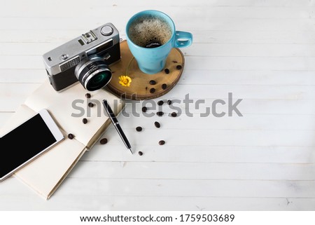 cup of coffee with vintage camera, Notebook and mobile phone on wooden table. close-up