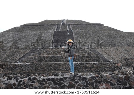 An Asian female tourist is standing on the steps in front of the Pyramid of the Sun in Teotihuacán Municipality near Mexico City, Mexico.