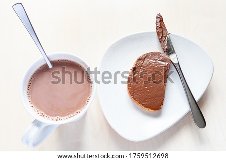 top view of cup with hot chocolate and toast with chocolatte spread on plate on table