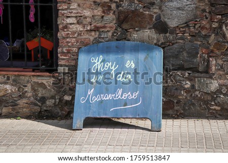 Quote board with the phrase in Spanish "Hoy es un dia maravilloso" with translation: "Today is a wonderful day" on a sidewalk in the city of Colonia del Sacramento - Uruguay