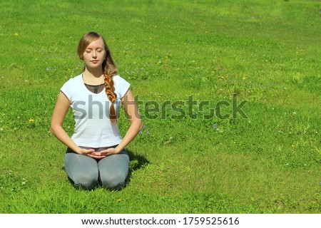Young woman of European appearance does yoga in summer nature. Woman sitting in hero pose, virasana. High quality photo for web and print with empty space for text and design.