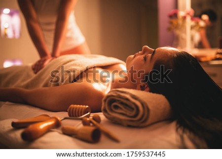 Girl receiving a maderotherapy massage while lying on her back on the massage bed with a towel behing her neck. 
