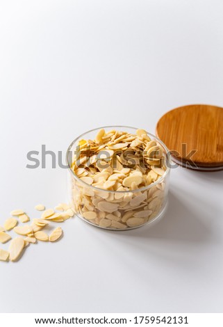 Almond flakes in a glass jar, wooden lid, white background