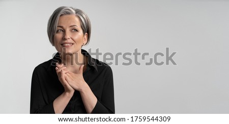 Smiling silver haired woman dreams clasped hands. Caucasian mature woman in black blouse looking to right side with copy or text spase. Cut out on white background. Horizontal blank or template. Royalty-Free Stock Photo #1759544309