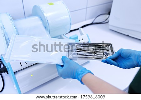 Sterilizing box. Sterilization of instruments. Dentist tools. Sterilization procedure. Hands in blue gloves holding dentist tools. Royalty-Free Stock Photo #1759616009