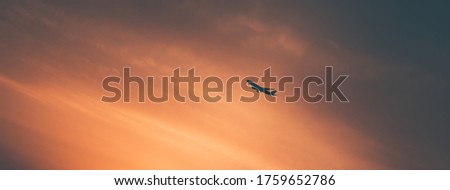 Silhouette of the Airplane over Beautiful Orange Sky. Sunset Background. Travel and Vacation Concept.
