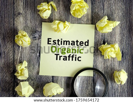 Organic traffic seo concept - text on yellow note sheets on a dark wooden background with crumpled sheets and a magnifying glass