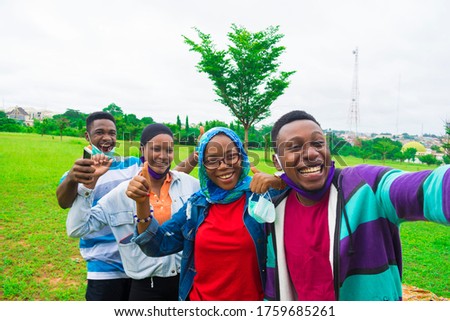 young black friends standing in a park and taking a selfie from the camera