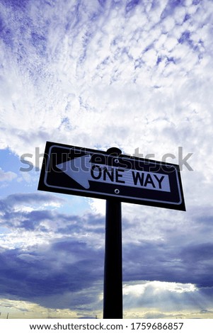       One Way Street Sign with blue sky and clouds in background.                         