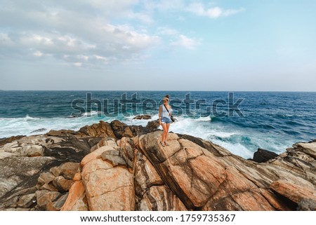Happy young torist woman  with camera taking pictures of the sea, sunset, evening, nature