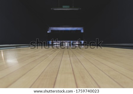 Leisure, entertainment and activities concept. Abstract background with copy space of old and dark parquet bowling track with white pins at the end of it