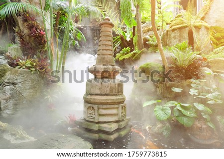 Beautiful Chinese stone pagoda in waterfall in the garden with mist and moning sun rise