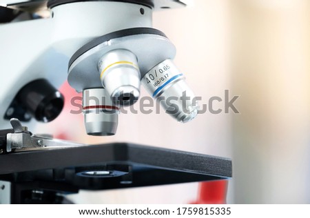Closed up of microscope in the laboratory with orange light and blurred background. Coronavirus and research concept