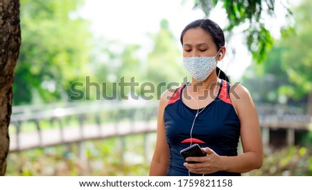 Portrait of Asia woman listening music from smartphone and jogging in the park