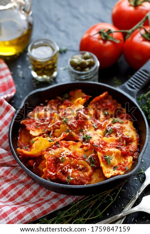Ravioli with tomato sauce sprinkled with Parmesan cheese and herbs in a cast iron skillet on a black background close up Royalty-Free Stock Photo #1759847159