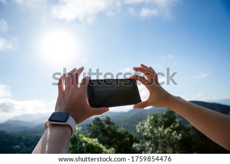 Hands using mobile phone taking picture in sunrise nature