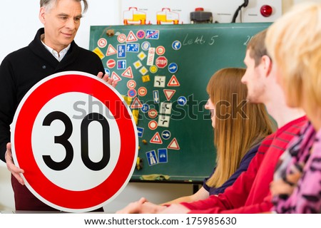 Driving school - driving instructor and student drivers with a tempo thirty Road sign, in the background are traffic signs