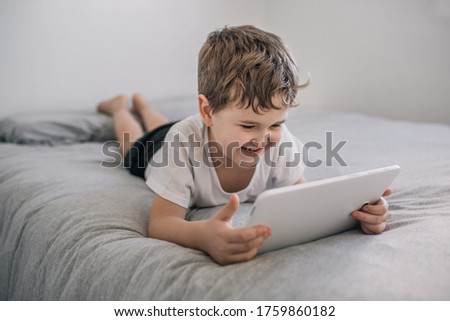 boy (6-7 years old) smiling using a tablet