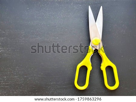 
metal scissors with yellow, green plastic handles isolated on black background