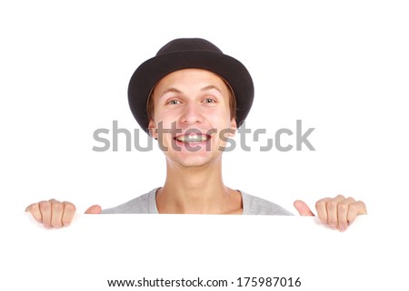 Young teenage boy hiding behind a billboard and smiling on camera isolated on white background