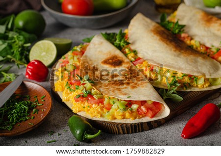 Fresh scrambled eggs with crispy tortillas, cheese, herbs and vegetable
