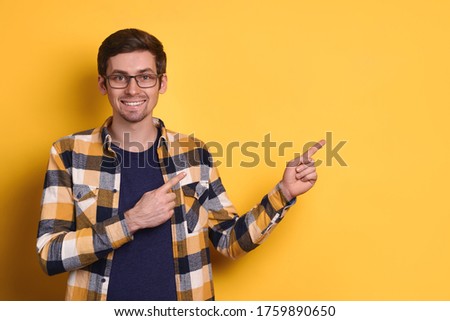 Young happy man over isolated yellow background amazed and smiling to camera while pointing with finger to copy space for text, presenting product, store, discount, shop, education. Promotion concept