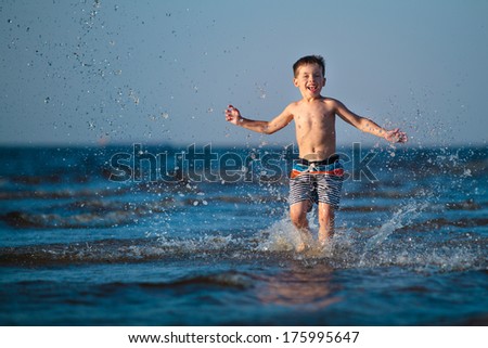 Little boy running through the water at beach