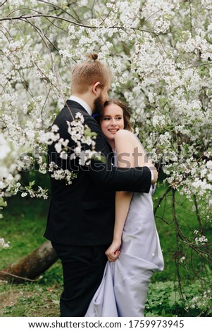 young beautiful couple in the garden against the background of cherry blossoms
