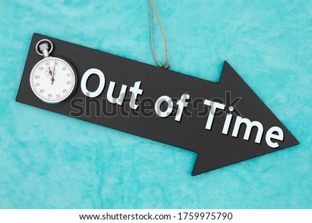 Out of Time type message on hanging arrow chalkboard sign with stopwatch on blue plush material