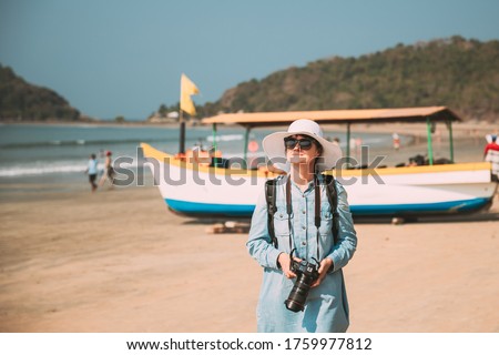 Canacona, Goa, India. Young Caucasian Lady Woman With Camera Standing On Famous Palolem Beach Near Arabian Sea In Summer Sunny Day
