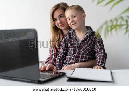 The child and mother study remotely. A woman helps her child. Online training. Home education and independence. Schoolchildren study during quarantine. Work with a laptop.
