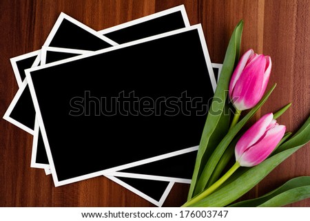 Blank photos and tulips on a wooden background