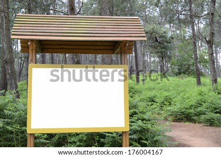 Billboard in green forest. White and wooden board