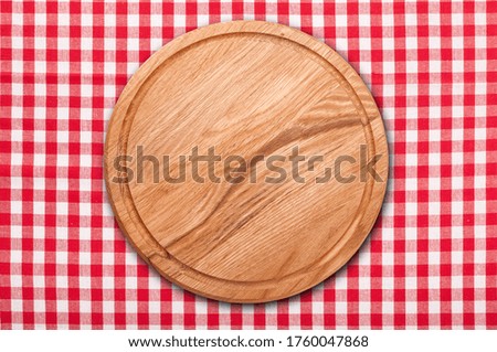 Empty pizza board and tablecloth on wooden deck table with napkin top view mockup