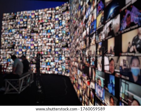Blur large LED screen show many people's faces join big online event or virtual reality live conference. Big video call seminar, Work from home, Social distancing, New normal event production. Royalty-Free Stock Photo #1760059589