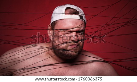 Picture of fat man tangled in black threads on red background