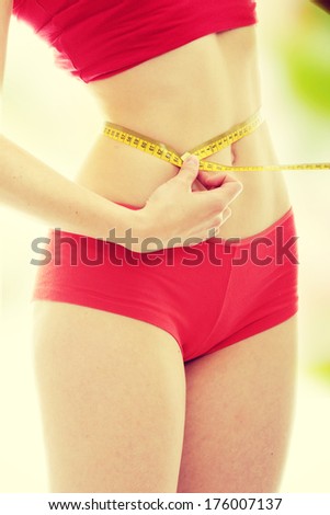 Beautiful young caucasian woman measuring her body with tape