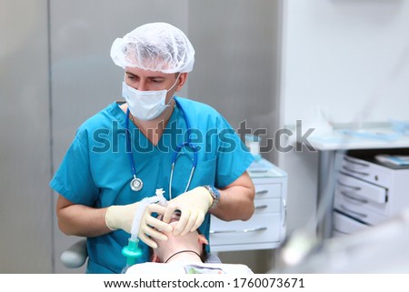 The doctor, the emergency physician places the child under anesthesia. Preparation before surgery. Concept of health care and life saving. Copy space. Royalty-Free Stock Photo #1760073671