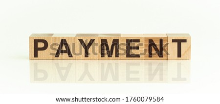 Wooden Blocks with the text: PAYMENT. The text is written in black letters and is reflected in the mirror surface of the table. New business relaunch startup concept.