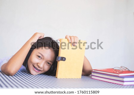 Portrait Asian young girl sitting with book and white background in student uniform.