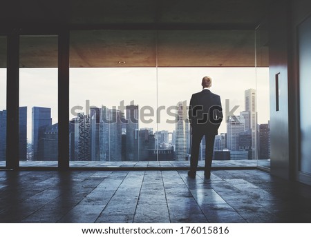 Businessman looking at city through window